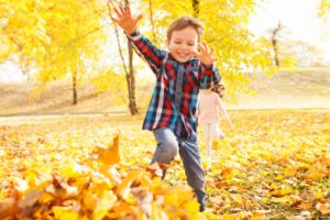 Young boy jumping in a pile of leaves