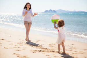 Parent and child playing with ball at beach