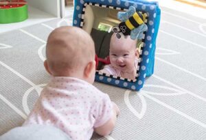 Infant looking in mirror laughing